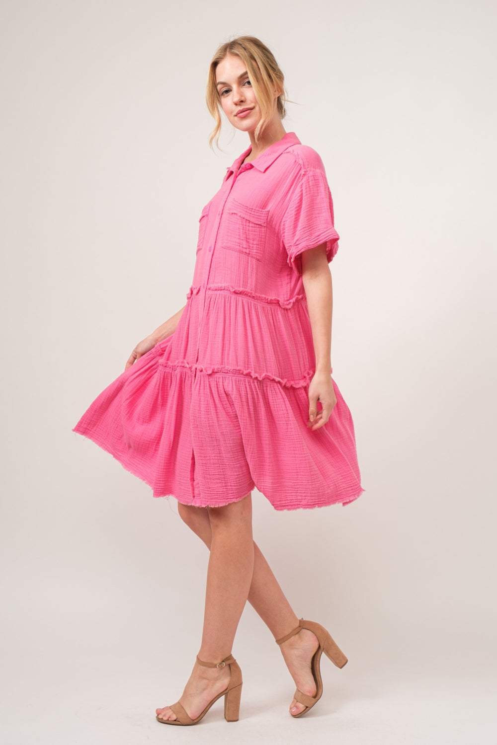 Raw edge tiered shirt dress in pink with raw hem, buttoned front, and tiered design.