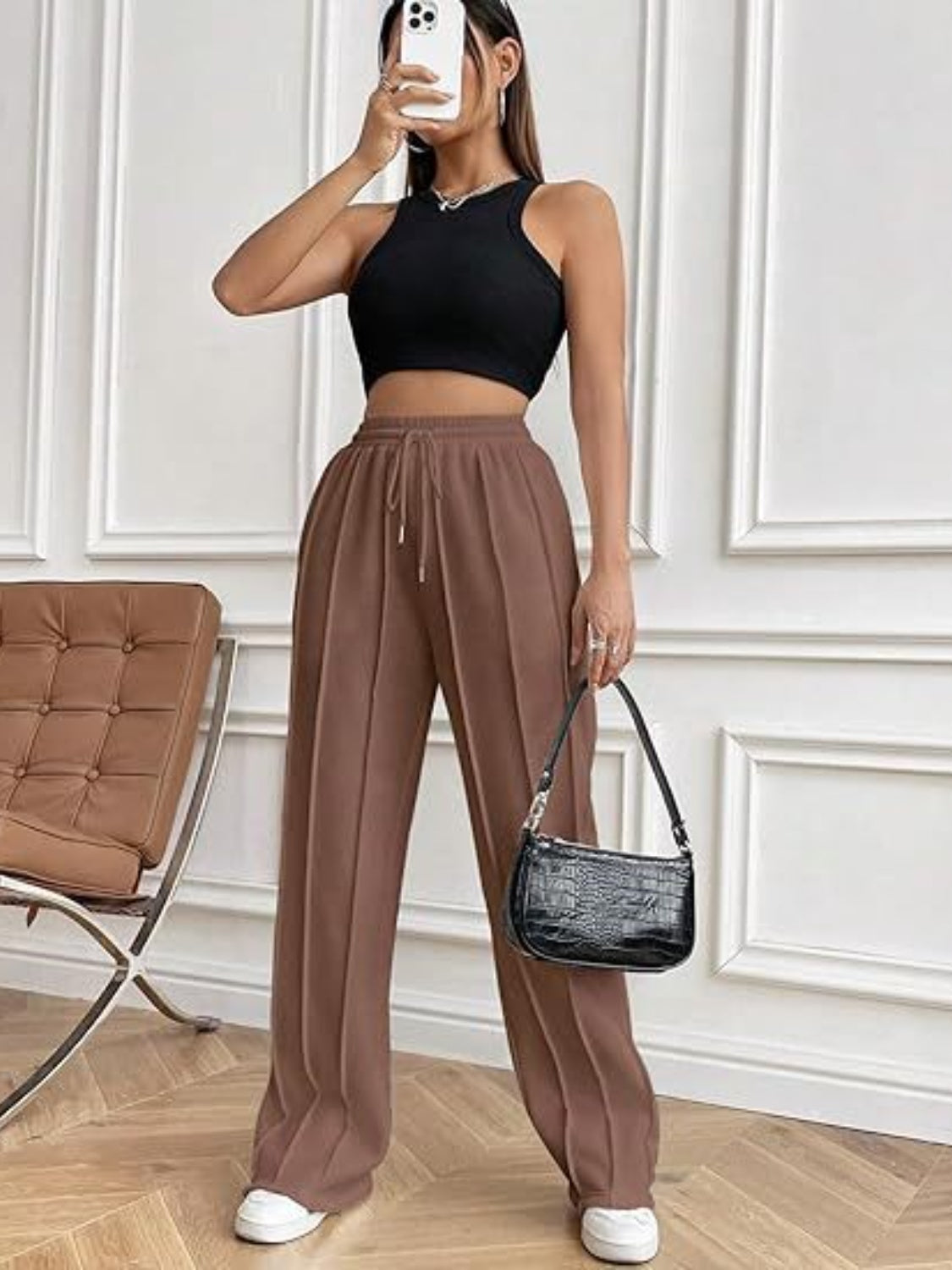 Wide leg drawstring pants with pockets, worn by model, paired with a black top and casual shoes.
