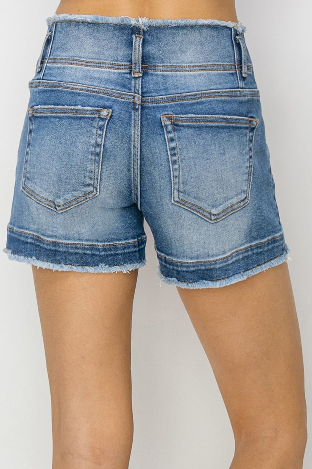 High rise seam detail denim shorts with raw edge hem, showcasing back pockets.